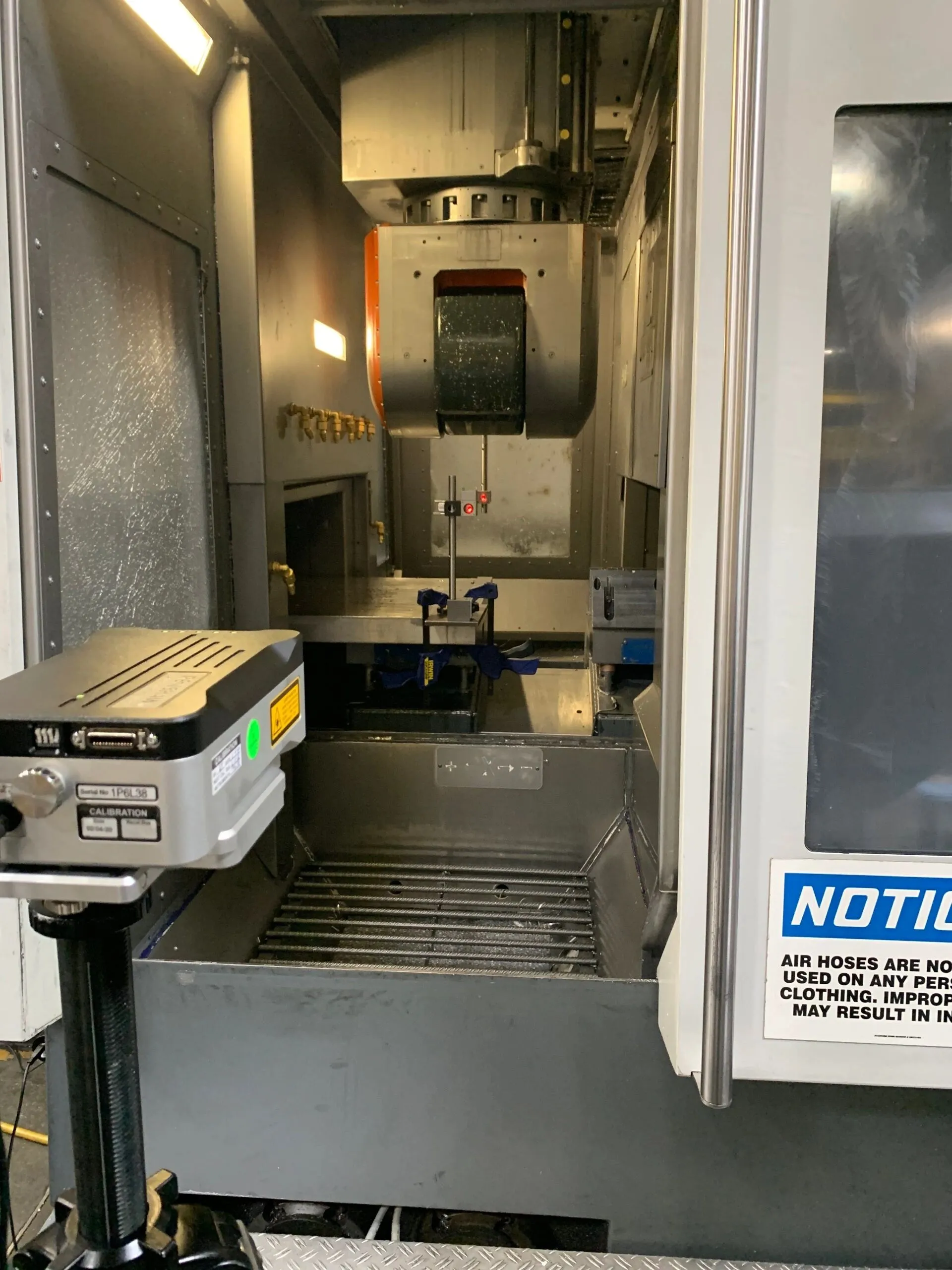 Laser unit on a tripod in front of a vertical machining centre